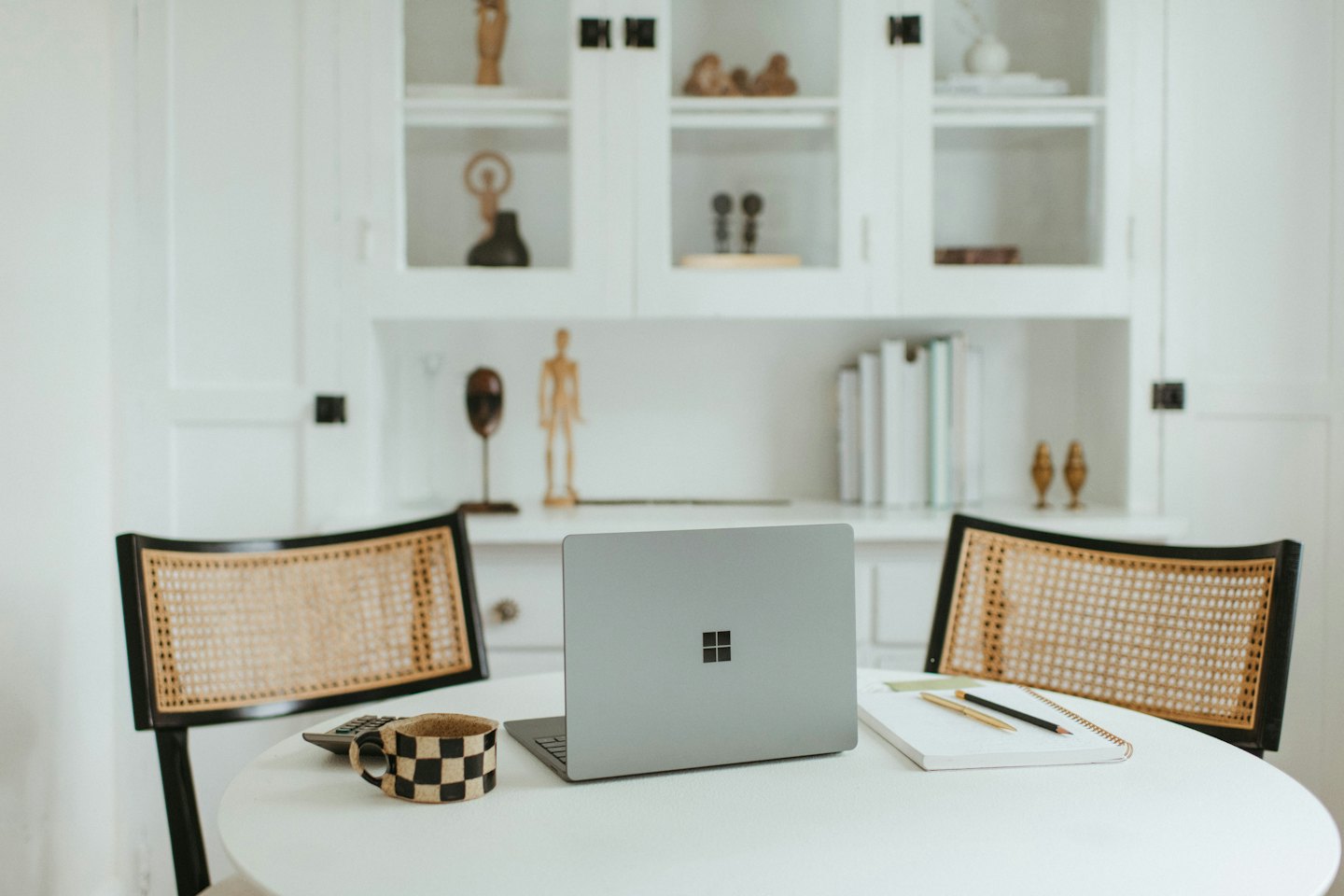 Laptop und Büromaterial auf einem runden Tisch zwischen Stühlen.